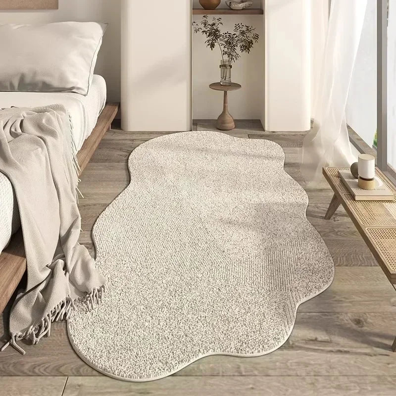 A light beige irregular plush area rug placed on a wooden floor in a modern living room setting.
