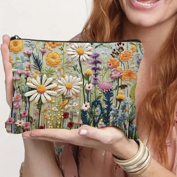 A hand holds a floral double-sided cosmetic storage pouch featuring various dried flowers and greenery.