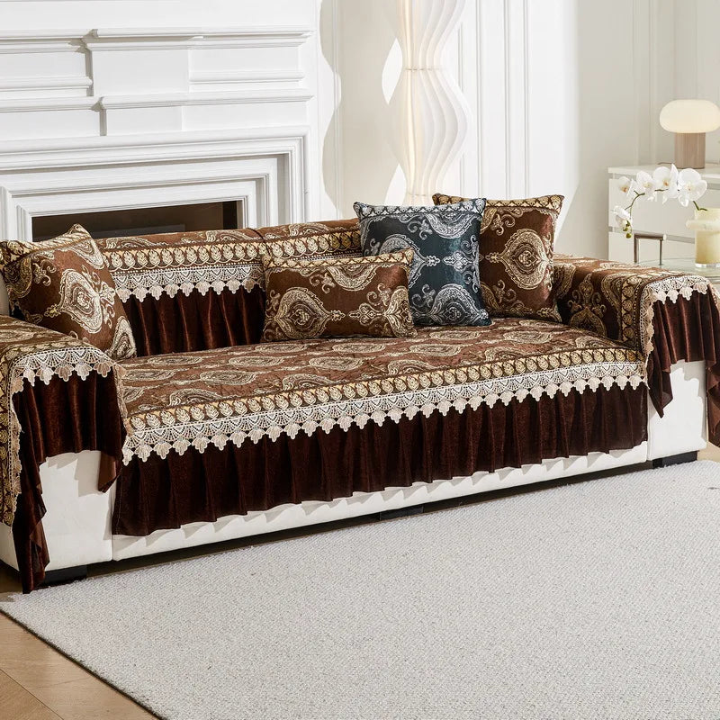 A brown and gold patterned quilted sofa cover with decorative trim and accent pillows on a white sofa.