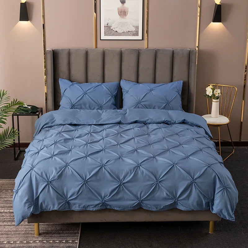 A blue quilted bedding set featuring a tufted headboard and gold accents in a bedroom setting.