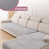A light beige L-shaped sofa covered in gray flannel fabric with quilted detailing.