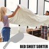 A person is using a bed sheet sorter tool to fold and organize bedding on a bed.