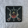 A black tactical skull patch featuring a metallic skull design with arrows pointing outwards.