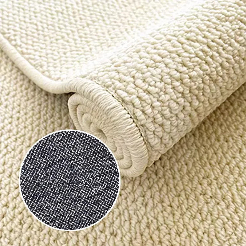 A rolled natural sisal jute rug showing a close-up of the woven texture and dark gray fibers.