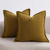 Two olive green textured boucle throw pillows resting on a light gray sofa.