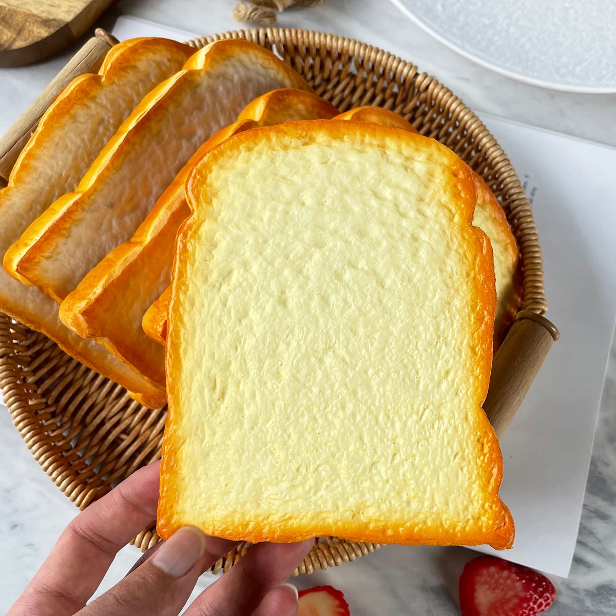 A hand holds a golden brown toast slice in a woven basket for food photography.