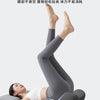 A person lying down with their legs raised, using a gray ergonomic memory foam leg/back support product.