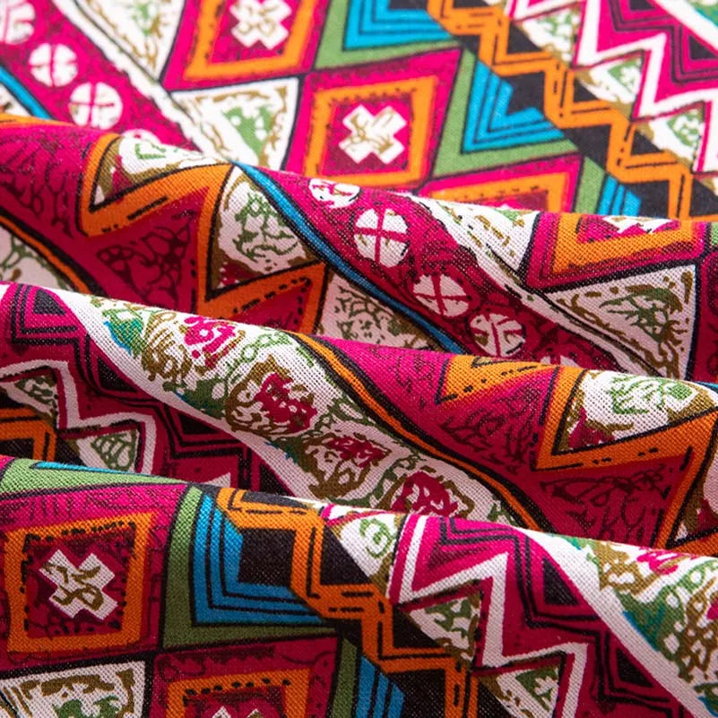 Close-up of vibrant bohemian printed linen fabric featuring geometric patterns in pink, orange, green, and white.