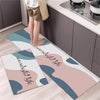 A rectangular rug with a diamond print featuring soft pink and blue wavy shapes is placed on a kitchen floor.