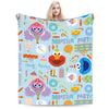 A person is holding a colorful flannel throw blanket featuring Monster Party themed cartoon characters and text.