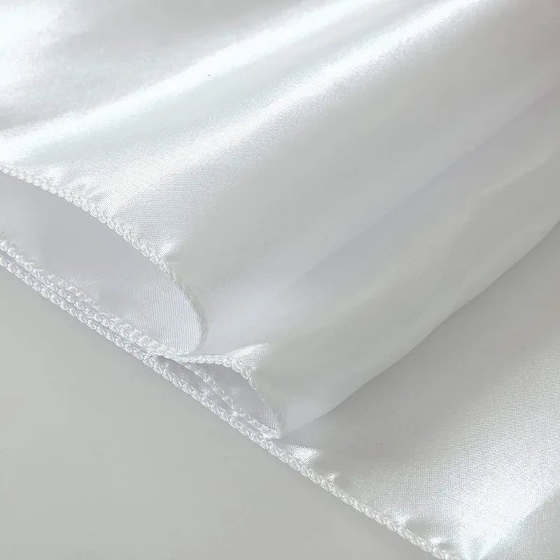 White satin table runner draped and folded on a light surface.