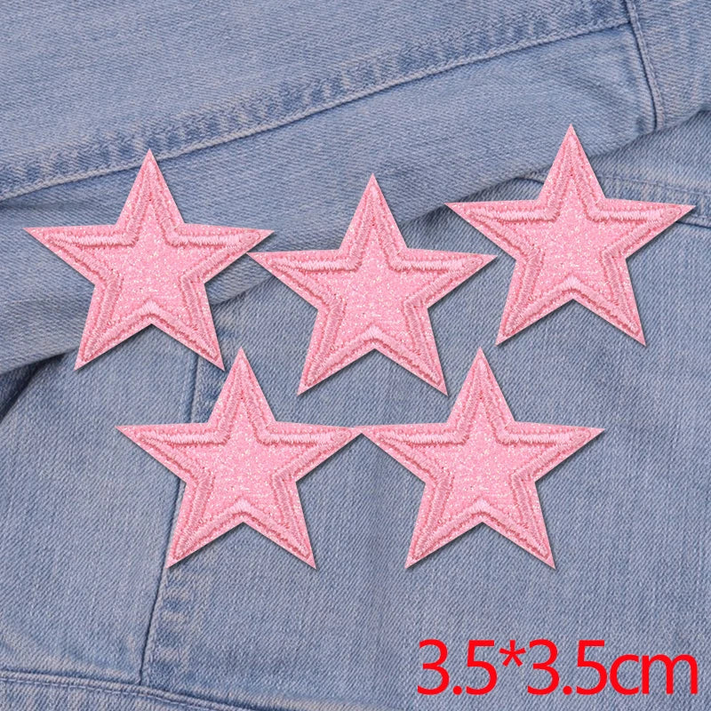 Five pink glitter star patches embroidered on a denim fabric