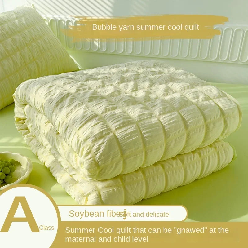 A stack of yellow bubble yarn summer cool quilt with a label describing it as soybean fiber and delicate for maternal and chi