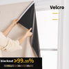 Hands are adjusting black blackout curtains in a window frame, showing the fabric texture and Velcro fastening.