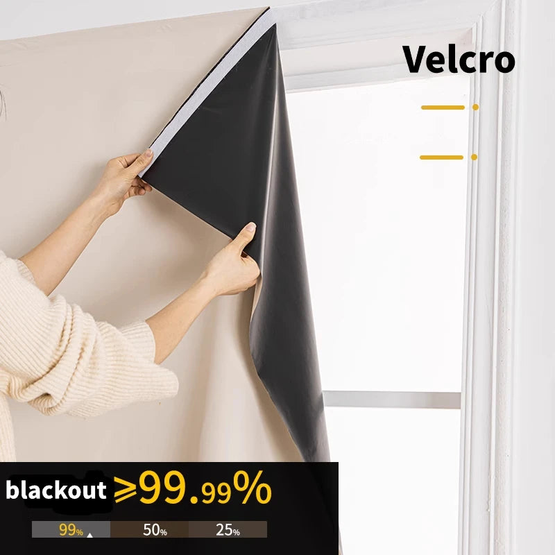 Hands are adjusting black blackout curtains in a window frame, showing the fabric texture and Velcro fastening.