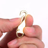 A hand holds a gold-colored zipper slider puller repair kit tool.
