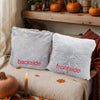 Two gray faux fur throw pillow covers labeled backside and frontside resting on a beige fabric.