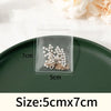 Clear plastic storage bag containing silver-colored pearl and gold-toned jewelry pieces on a dark green plate.