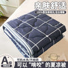 A stack of navy blue quilted blankets with white stitching and a logo on a white surface.