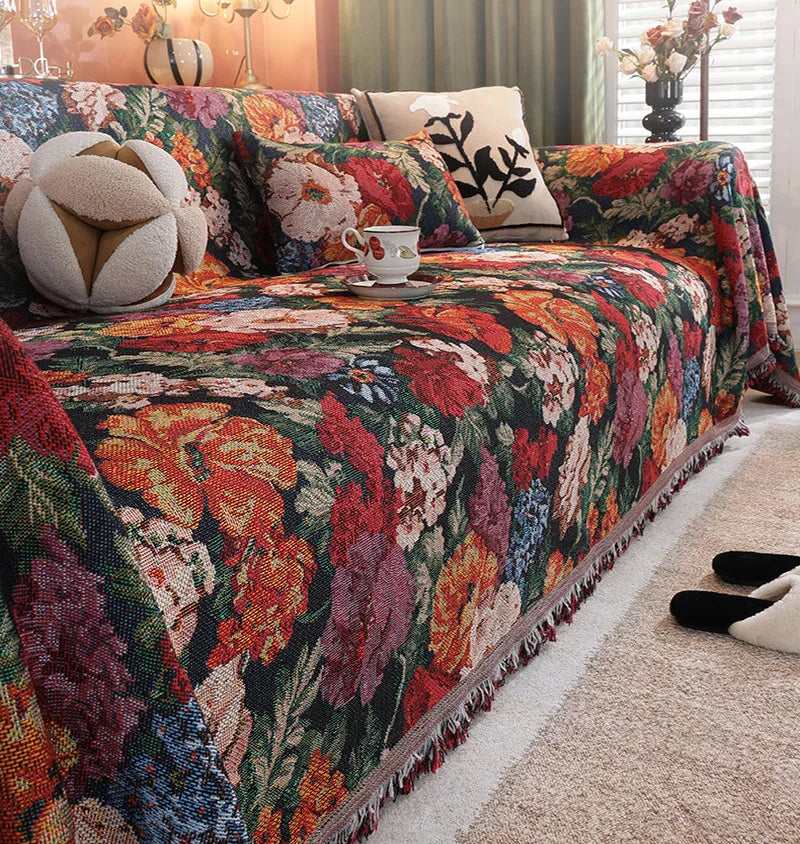 A richly colored floral jacquard sofa throw blanket draped over a sofa with patterned pillows.