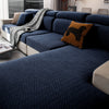 A deep blue stretchy polar fleece sofa cover with a woven texture and accent pillows in brown and gray.
