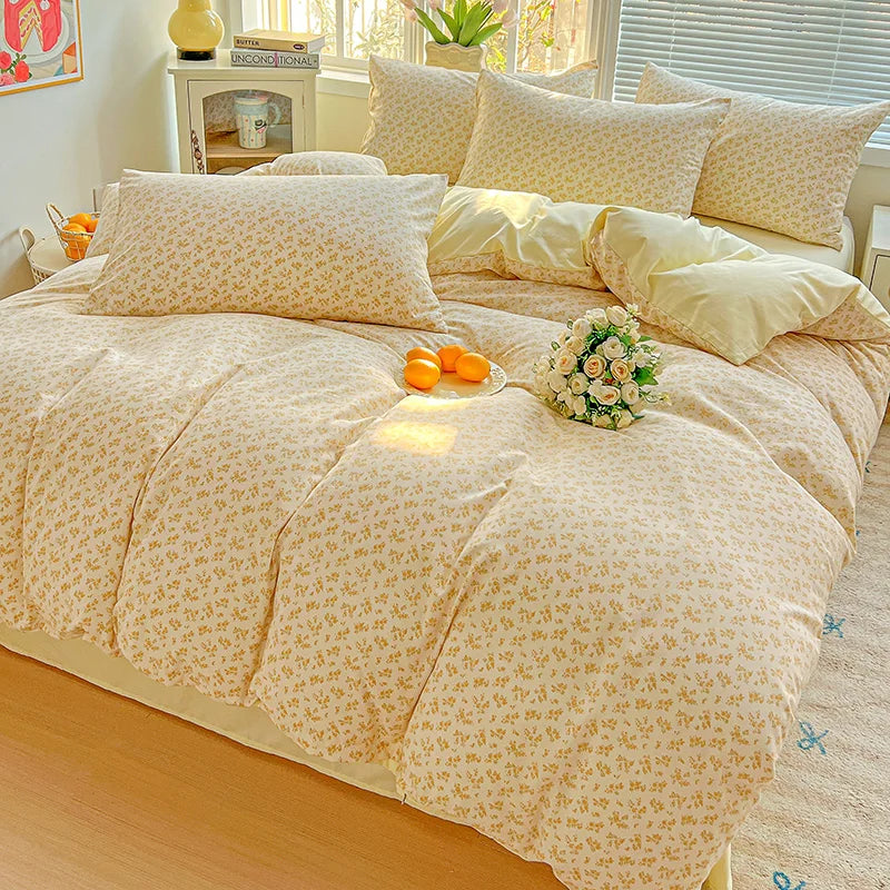 A light beige floral printed bedding set with matching pillows and a decorative arrangement on a bed.