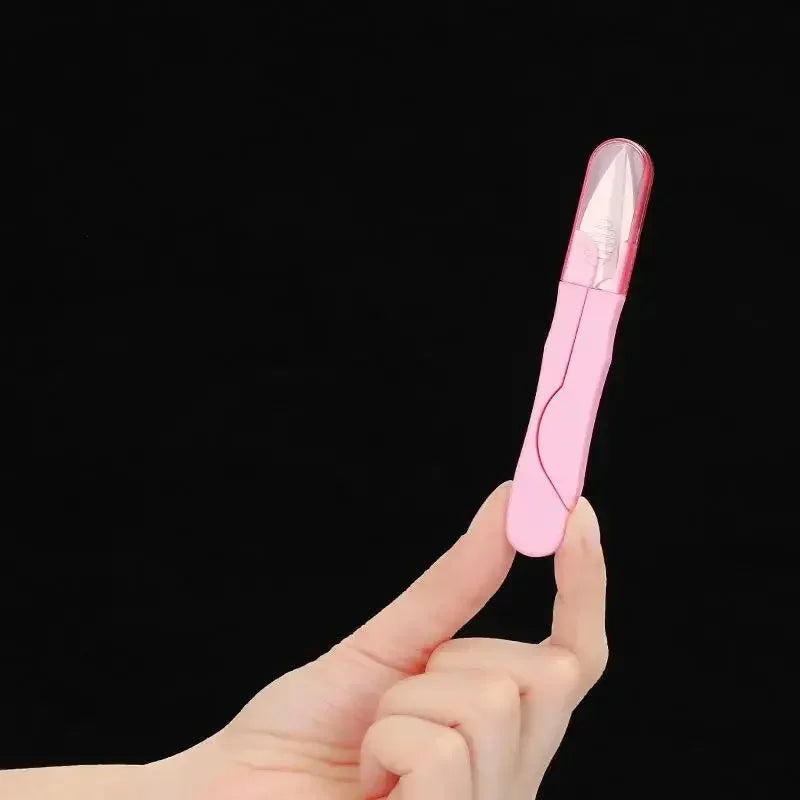 A hand holds a pink stainless steel sewing and embroidery scissors set against a black background.