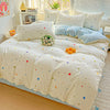 A white floral printed bedding set with light blue accents and pillows on a bed.