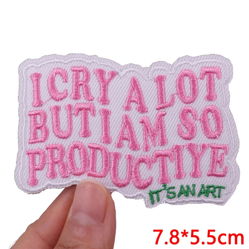 Pink embroidered letter iron-on patch spelling out ICRYALOTBUTIAMSOPRODUCTIVE ITsANART