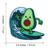 An embroidered patch depicting a smiling green avocado character swimming in blue and teal ocean waves.