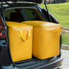 A yellow heavy-duty waterproof storage bag with reinforced handles is placed in the trunk of a car.