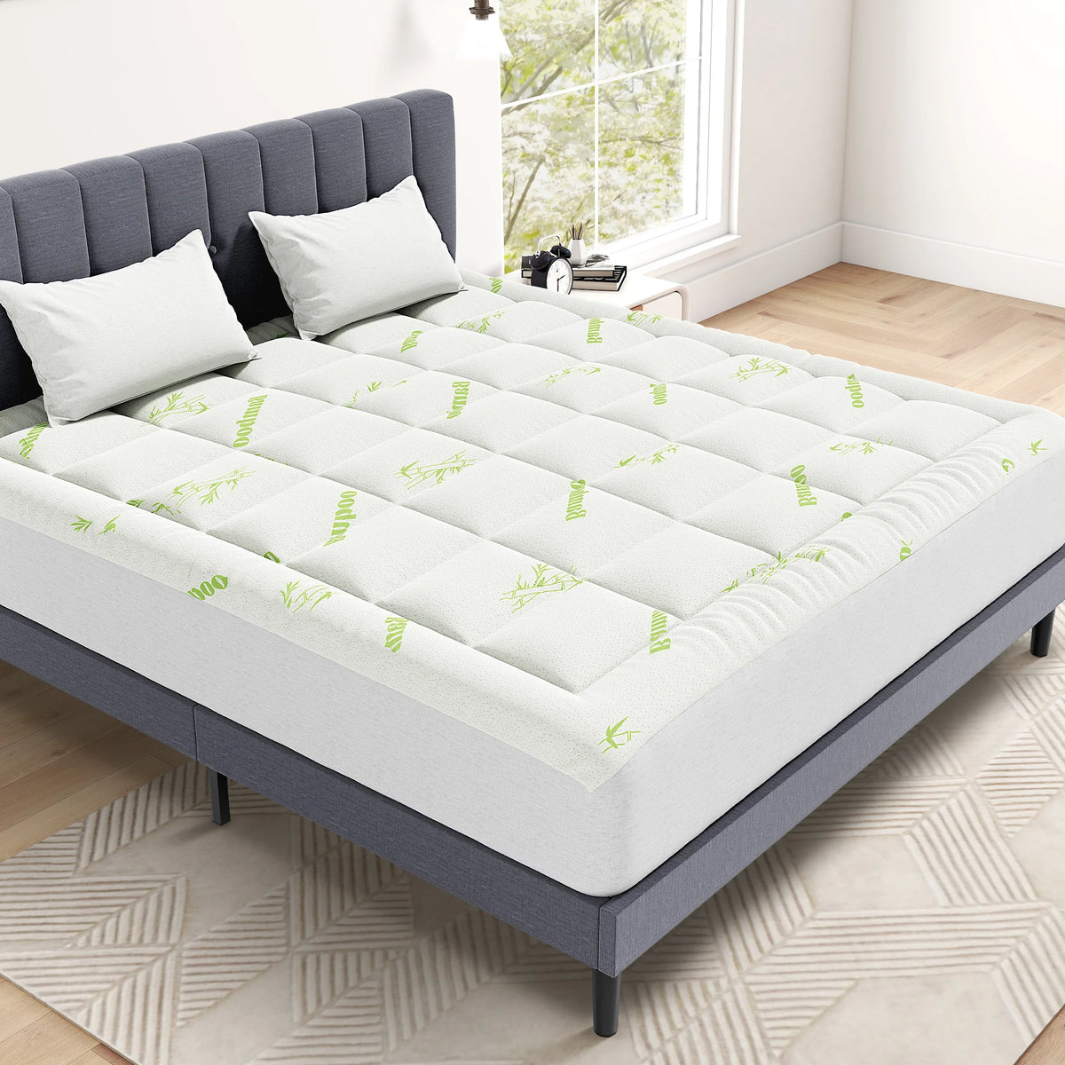 A gray mattress with a white bamboo viscose topper featuring green leaf patterns on a light wood floor.