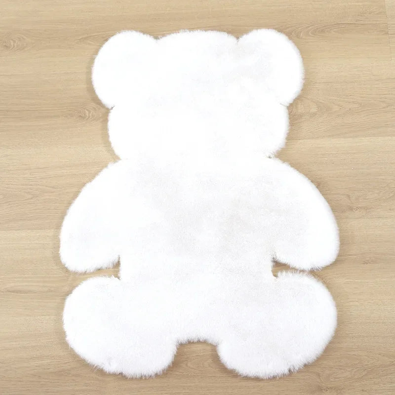 A white plush bear-shaped non-slip area rug lying on a wooden floor.