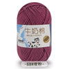 A skein of deep magenta milk cotton yarn with a label indicating stretch and fiber content.