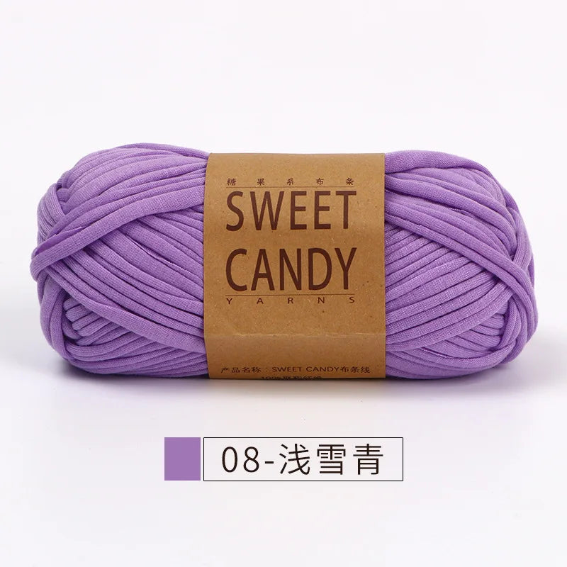 A skein of purple hand-dyed fabric strip yarn labeled Sweet Candy Yarns.
