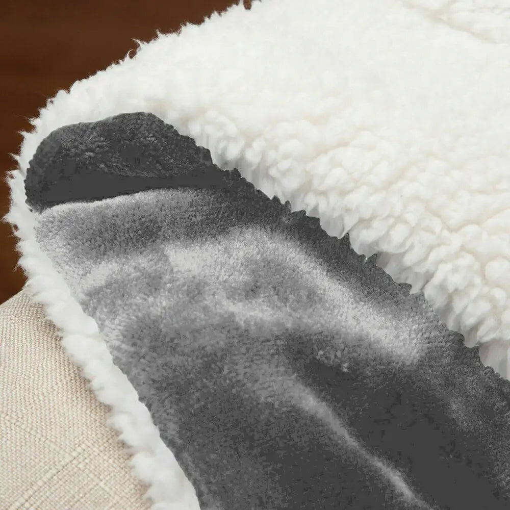 Close-up of a double-sided sherpa fleece blanket showing a light beige side and a dark gray side.