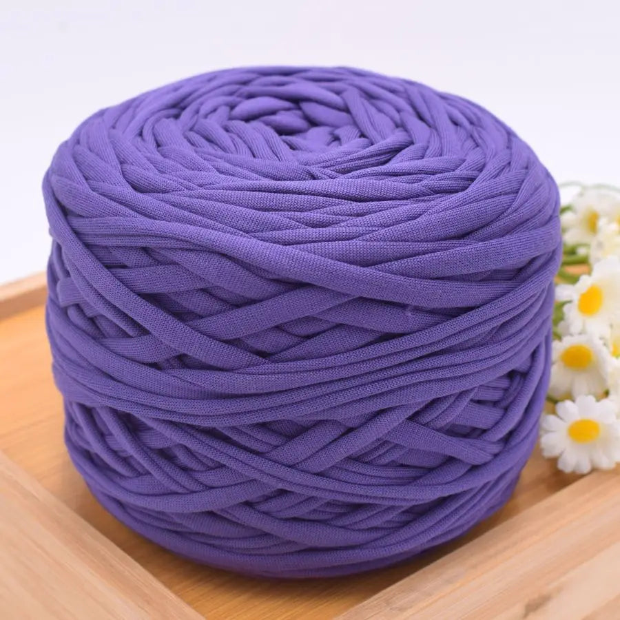 A ball of purple craft yarn for knitting and DIY displayed on a wooden surface.