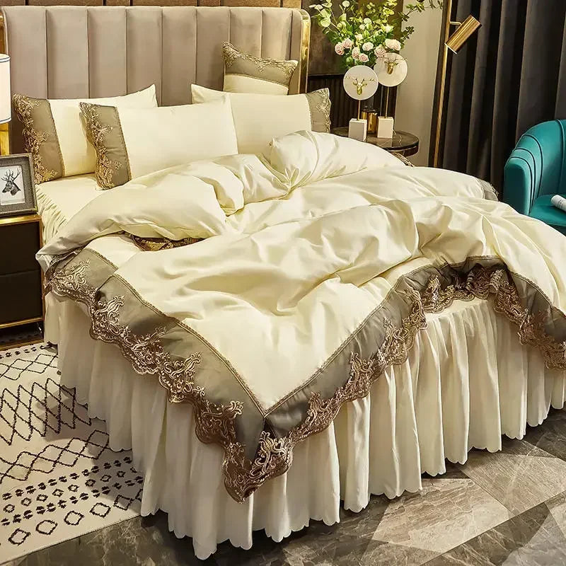 A luxurious bed set featuring a cream duvet and skirt with gold lace edging in a bedroom setting.