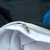 A close-up of a white fabric with a gold zipper pull, showing the interior of bedding.