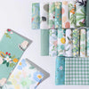 Rolls of floral cotton fabric in various greens and whites for quilting and crafting projects