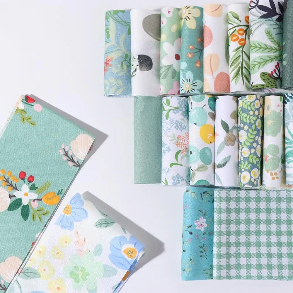 Rolls of floral cotton fabric in various greens and whites for quilting and crafting projects
