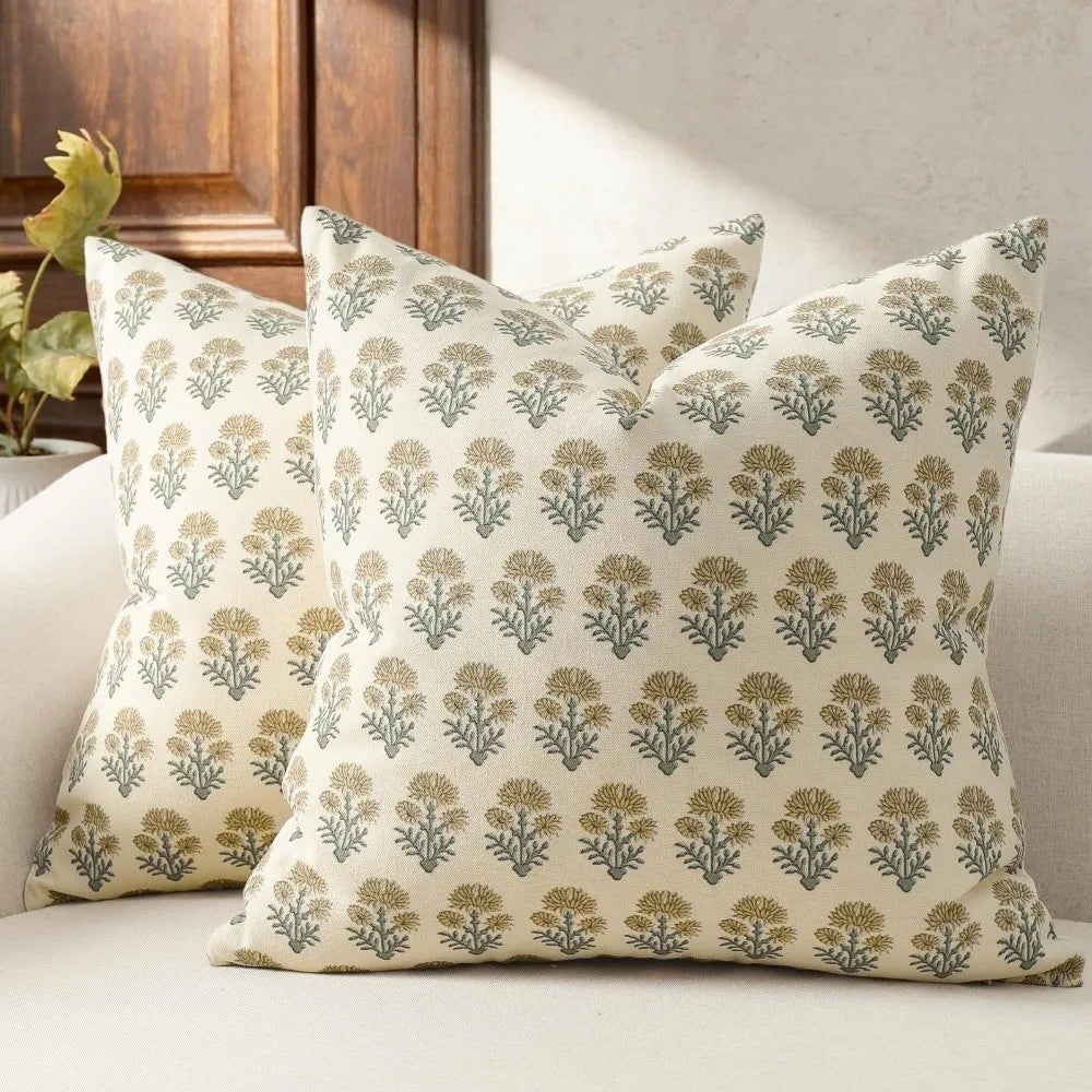 A beige throw pillow cover with a repeating pattern of olive green and gold floral motifs.