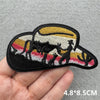 A black embroidered iron-on patch depicting a silhouette of a cowboy riding a horse against a striped background.