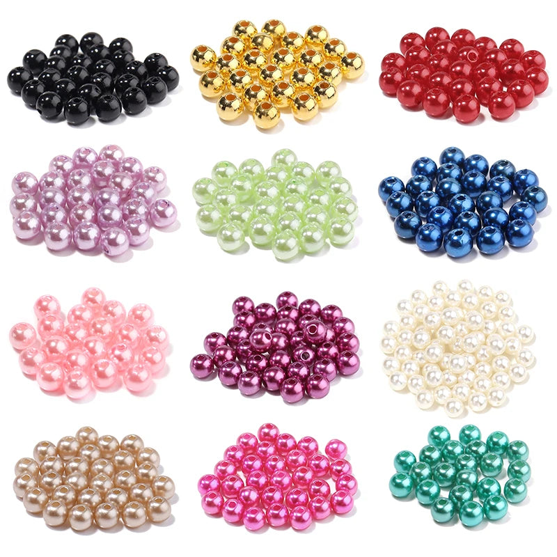 A collection of various colored imitation pearl beads in black, gold, red, pink, purple, white, and green.