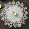 Elegant lace-trimmed round tablecloth with a white floral pattern and a central small bowl.