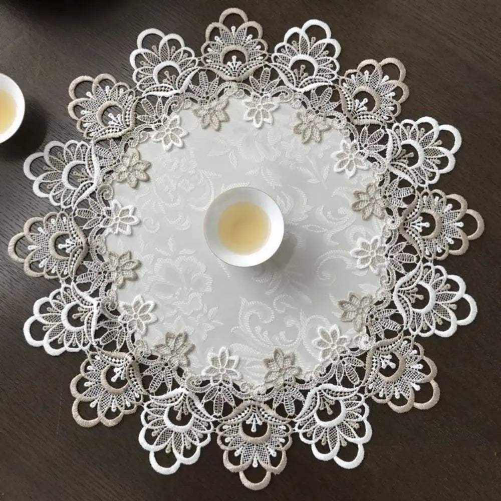 Elegant lace-trimmed round tablecloth with a white floral pattern and a central small bowl.