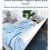 A light blue bamboo fiber blanket is spread on a white bed, showing its breathable fabric texture.