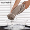 A hand is dipping a gray chenille sofa protector cover into a clear bowl of water for washing.