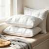 A stack of white hotel-grade memory foam sleeping pillows resting on a light-colored surface next to a window.