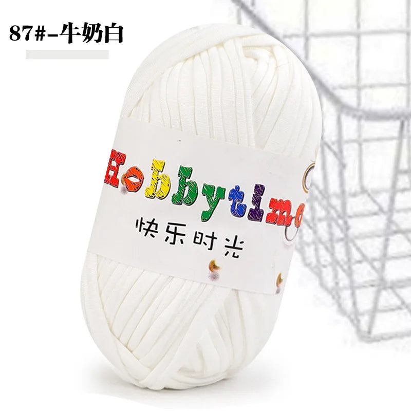 A ball of white craft yarn labeled Hobbytime with Chinese text, shown against a wire mesh background.